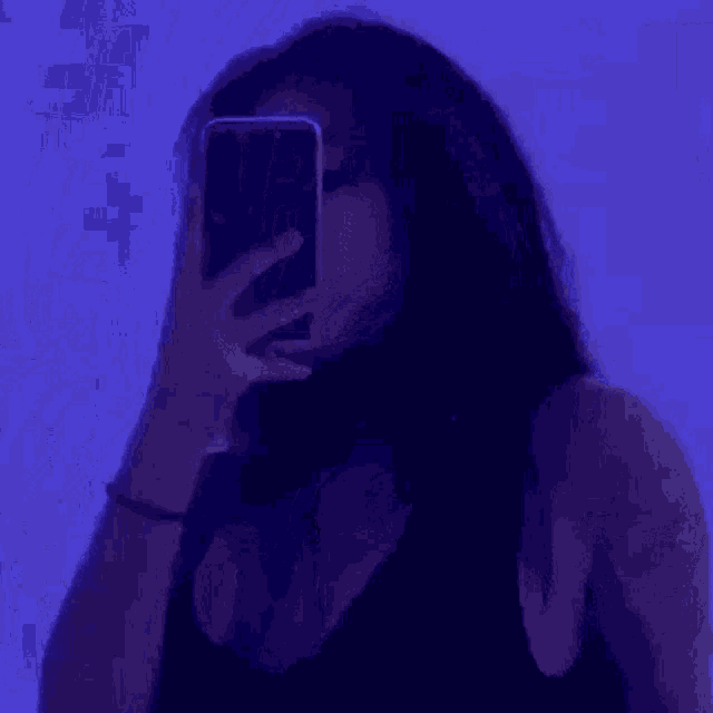 a woman is taking a selfie with her phone in a purple room .