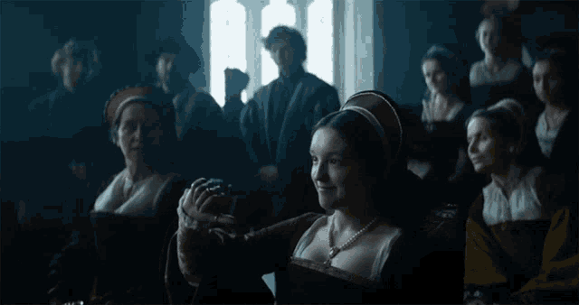 a group of people are sitting in a dark room with a woman sitting in the middle