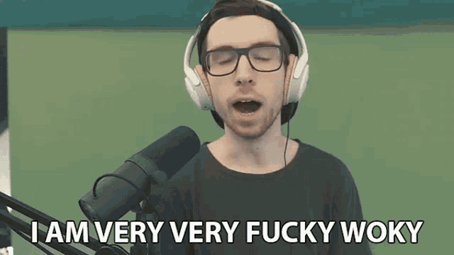 a man wearing headphones and glasses is singing into a microphone and saying i am very very fucky woky