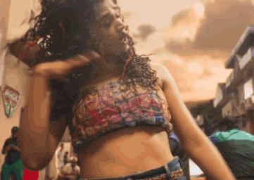 a woman in a crop top and shorts is dancing in the street
