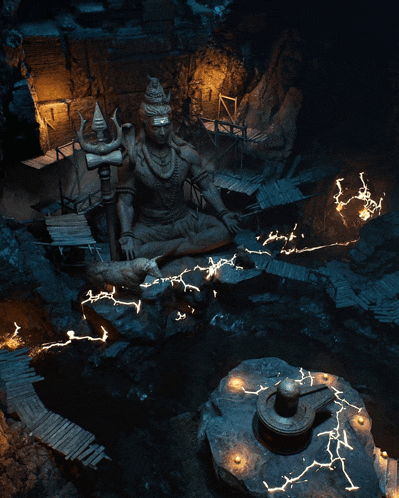 a statue of shiva sits in a cave surrounded by candles