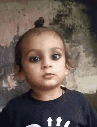 a little girl wearing a black shirt with arrows on it looks at the camera