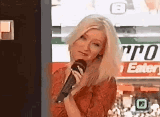 a woman is holding a microphone in front of a sign that says metro eatery .
