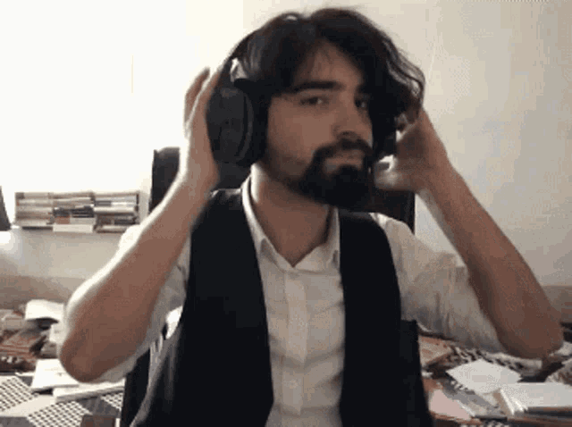 a man with a beard wears headphones and adjusts his hair