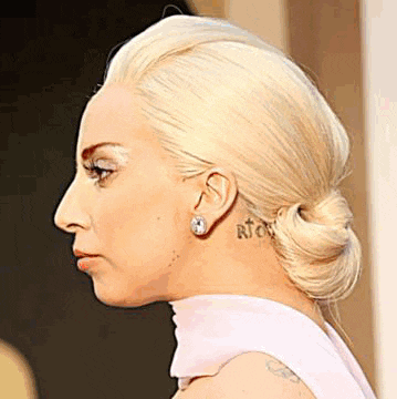 a close up of a woman 's face with a tattoo on her neck and ear .