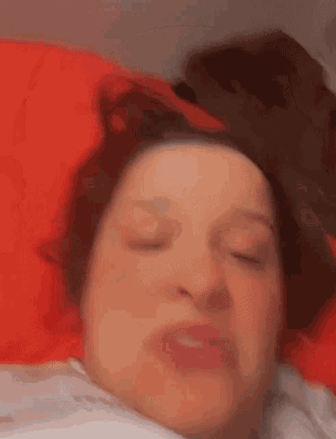 a woman is making a funny face while laying in bed with her eyes closed .