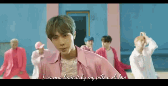 a man in a pink shirt is standing in front of a group of men in pink clothes .