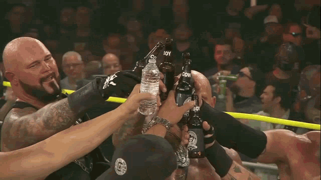 a man in a wrestling ring holds up a bottle of water and a bottle of beer with the word com on it
