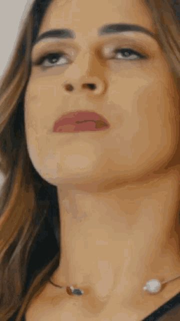 a close up of a woman 's face with a necklace on her neck