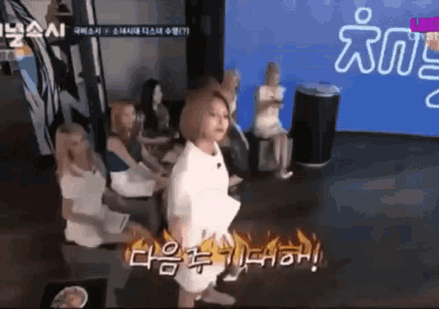 a group of women are sitting on a couch in a room and a woman is standing in the middle of the room .