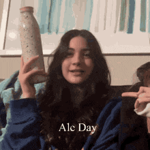 a girl in a blue sweatshirt is holding a bottle with the words ale day written on it
