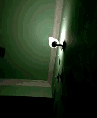 a light on a green wall with a shadow on it