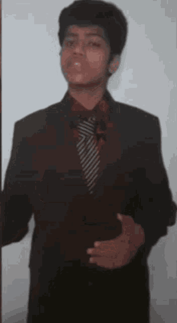a man in a suit and tie is standing in front of a wall .