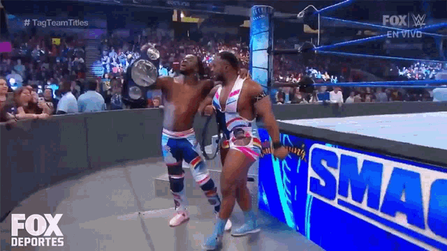 two wrestlers are dancing in front of a sign that says smackdown