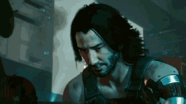 a man with long hair and a beard looks down at something