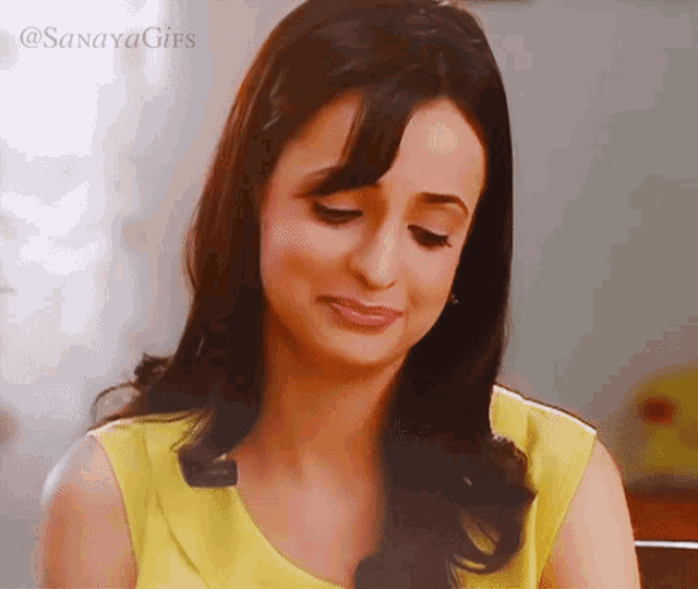 a woman in a yellow top is smiling with the words sanaya gifs written above her