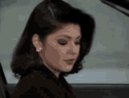 a woman is sitting in the back seat of a car and looking down .