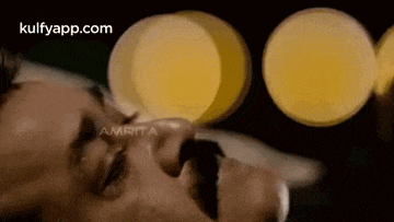 a man with a mustache is laying down with his eyes closed and a blurred background .
