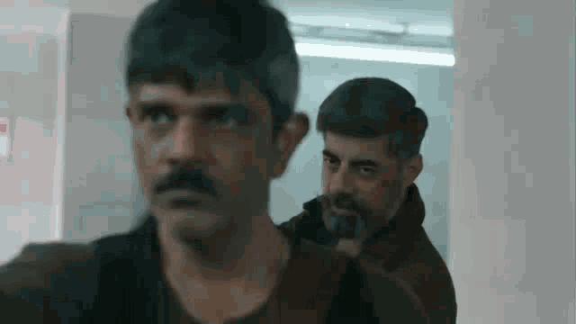 a man with a beard is standing next to another man in a room .