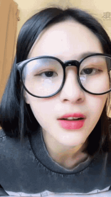 a close up of a woman wearing glasses and a grey shirt