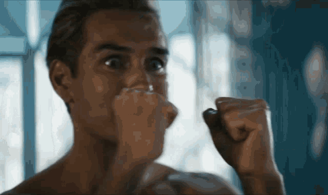 a man without a shirt is holding his fist up to his face