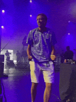 a man in a blue shirt with the word england on it is dancing on a stage