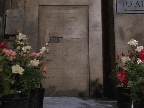 a sign that says to all is next to a door with flowers in front of it