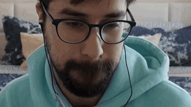 a man with a beard wearing glasses and ear buds