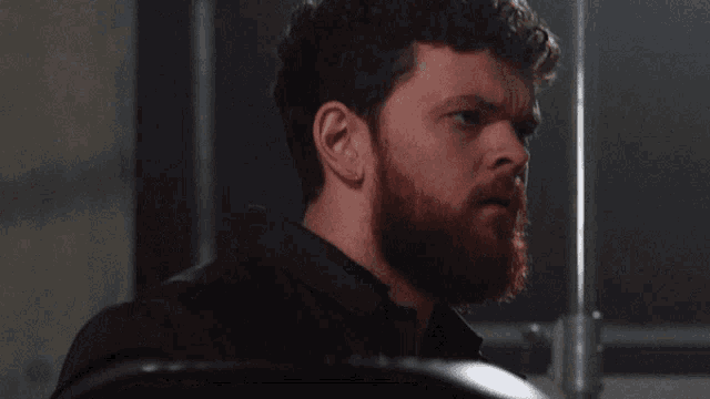 a man with a beard and a black shirt is looking at something