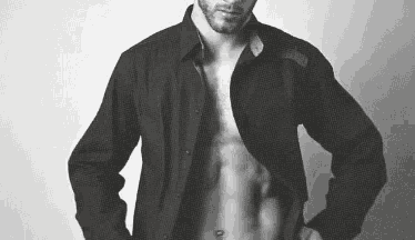 a man is standing in a black and white photo with his shirt open .