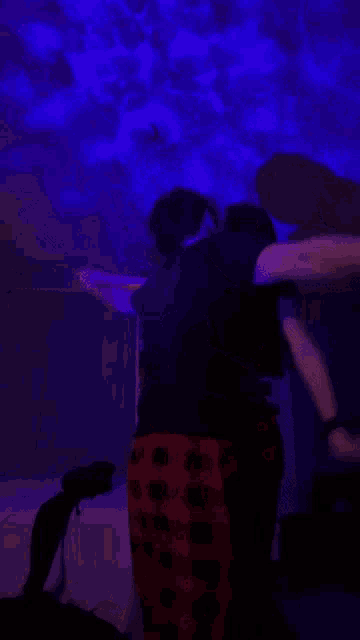 a man and a woman are dancing in a dark room with a blue light on the ceiling .
