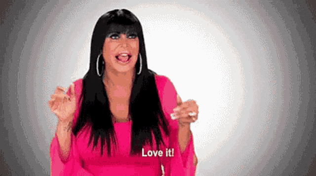 a woman in a pink dress is standing in front of a white background and saying `` love it '' .