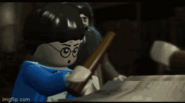 a lego harry potter character is holding a book in his hand