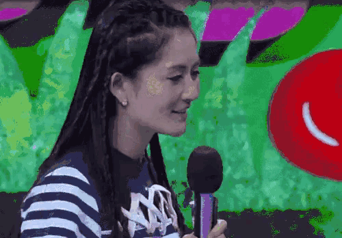 a woman is holding a microphone in front of a colorful background