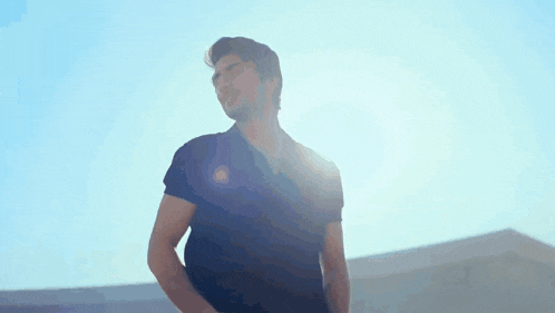 a man in a black shirt is standing in the sunlight