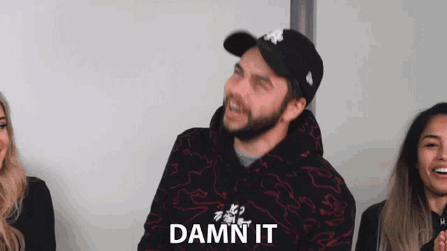 a man wearing a hat and a hoodie says " damn it "