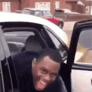 a man is getting out of a car and smiling .