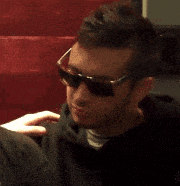 a close up of a man wearing sunglasses and a black sweatshirt
