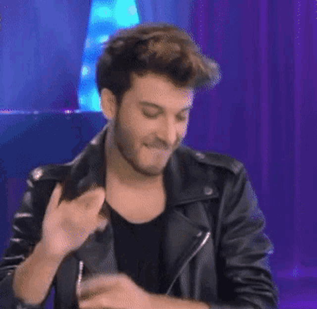 a man in a black leather jacket is dancing