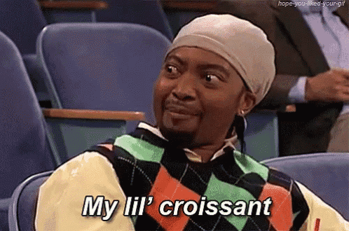 a man in a plaid sweater is sitting in a classroom and saying my lil croissant