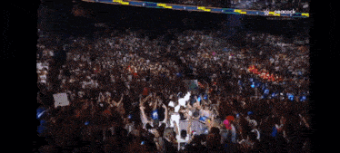 a crowd of people are gathered in a stadium watching a game on peacock