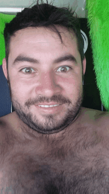 a shirtless man with a beard is smiling