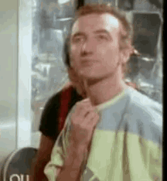 a man in a yellow and blue shirt is making a funny face and giving the middle finger .