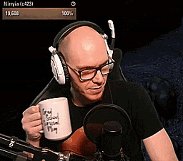 a man wearing headphones and glasses is holding a mug that says " god saving arsenal "