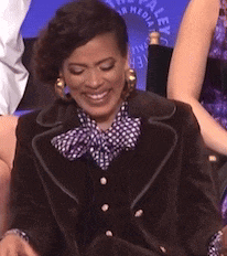 a woman wearing a brown jacket and a polka dot bow tie is smiling