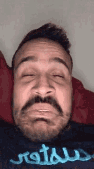 a man with a beard is making a funny face with his eyes closed .