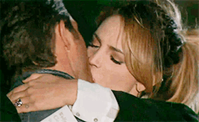 a man and a woman are hugging and kissing and the woman is wearing a ring