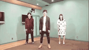 a group of people standing in a room with a television on the wall .