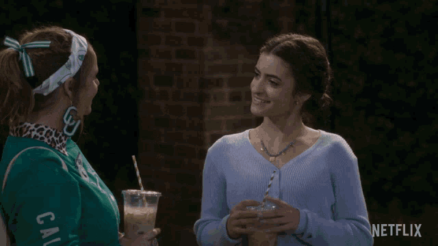 a woman wearing a cal university sweatshirt toasts another woman with drinks