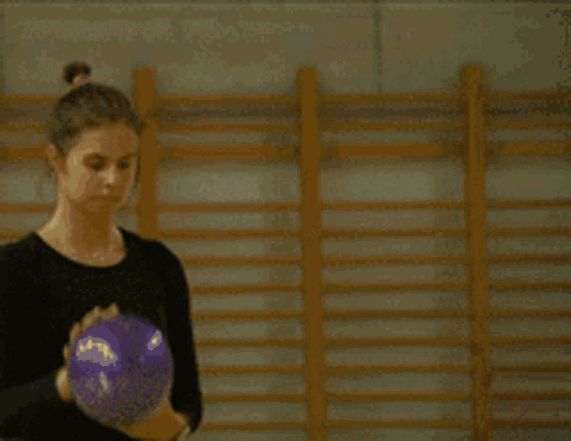 a girl in a pink ponytail is doing a routine on a purple mat
